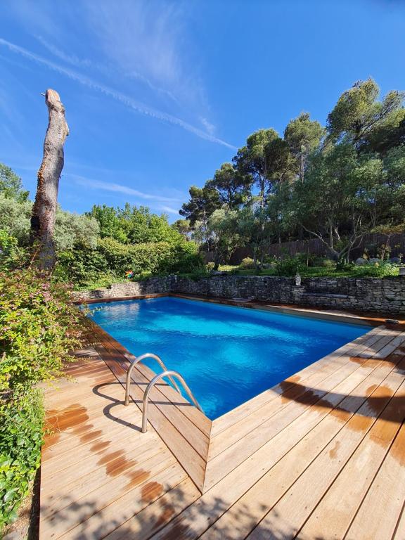 una piscina en una terraza de madera con un banco al lado en Le Mas des Anges, en Cheval Blanc