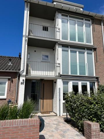 een groot wit huis met een veranda en een balkon bij Casa del Cisne 3 in Zandvoort