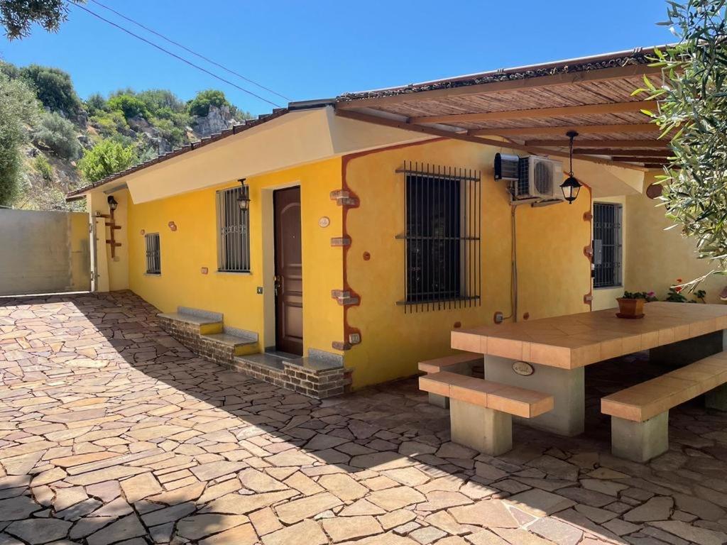 a yellow house with a picnic table in front of it at Holiday Home Marilu in Siniscola