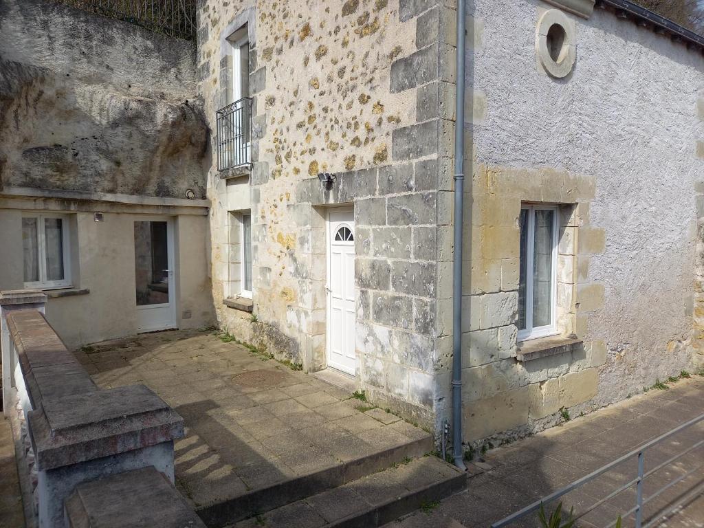 ein altes Backsteingebäude mit einer weißen Tür und einer Treppe in der Unterkunft Troglo Bel Être in Langeais