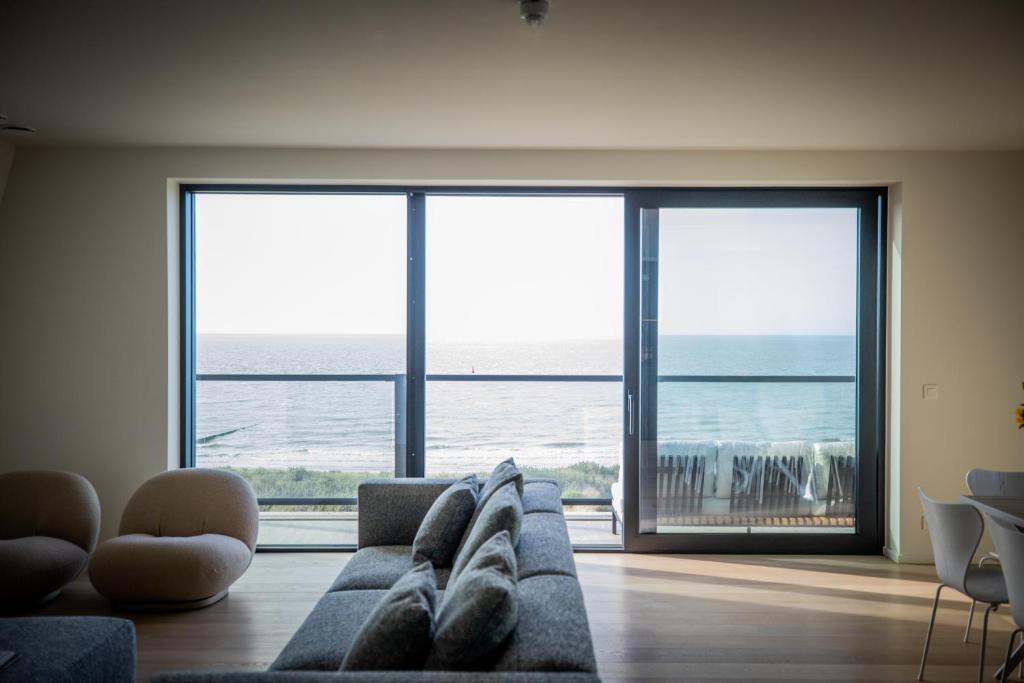 een woonkamer met een bank en uitzicht op de oceaan bij La Risacca, Luxurious, 3 bedroom, sea view design apartment in Cadzand