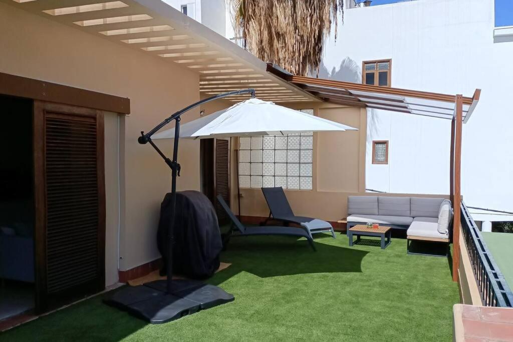 eine Terrasse mit einem Sonnenschirm, einem Sofa und einem Stuhl in der Unterkunft Luxury Penthouse, 50m2 terrace, downtown in Santa Cruz de Tenerife