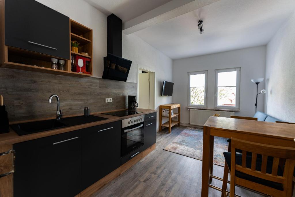 a kitchen with black cabinets and a wooden table at Ferienwohnung am Steinbach 1 in Thale