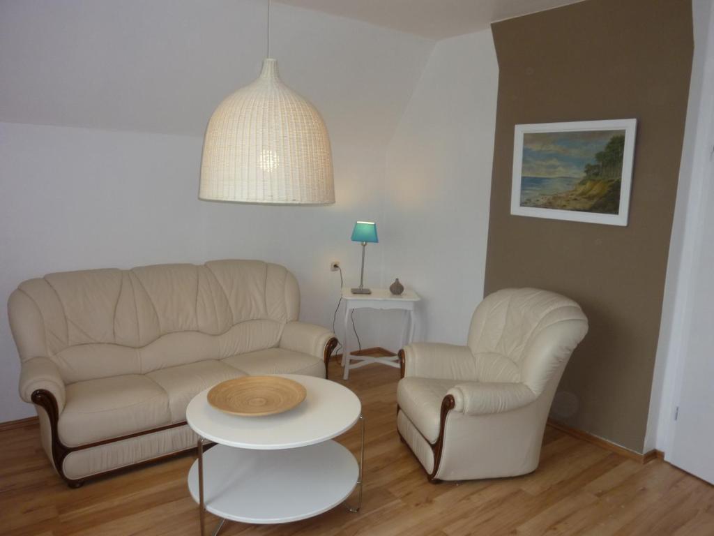 ein Wohnzimmer mit einem Sofa, 2 Stühlen und einem Tisch in der Unterkunft Kleine Sandburg Heiligendamm in Heiligendamm