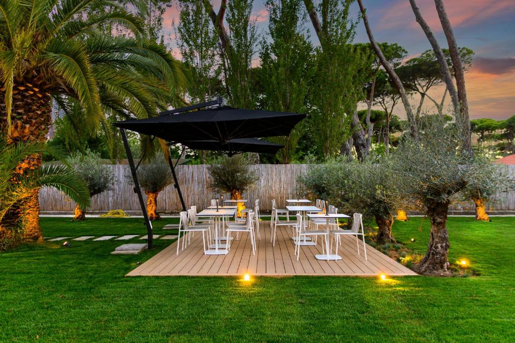 a group of white tables and chairs under an umbrella at Resort Miramonti in Forte dei Marmi