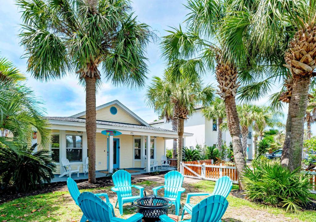 a group of chairs and palm trees in front of a house at Private Beach Access, Fenced Yard & Pet Friendly, Cabana Life Beach House in Destin