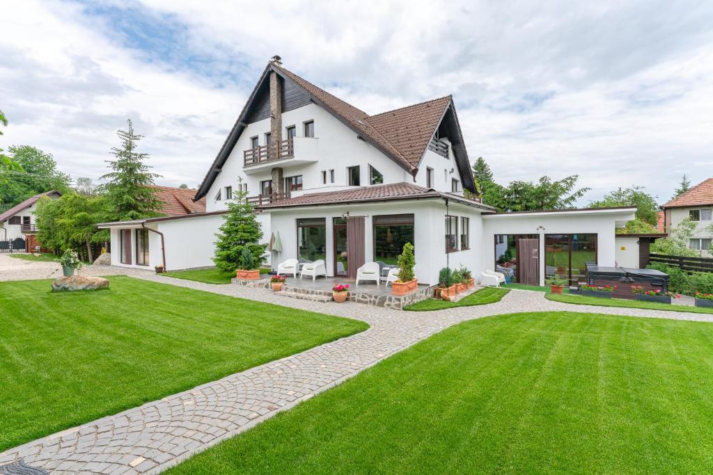 a large white house with a green lawn at Vila Trubadur - Adults Only in Bran