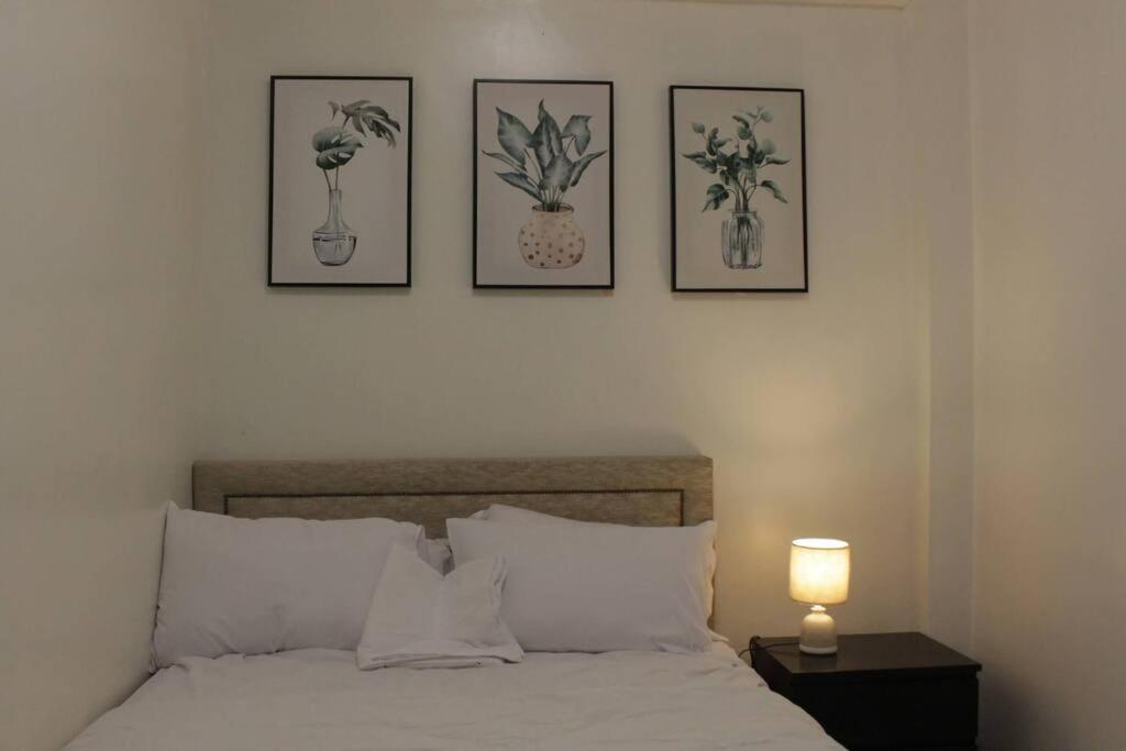 um quarto com uma cama com quatro fotografias na parede em A2J Executive 1BR Business Suite Near UP Los Baños em Los Baños