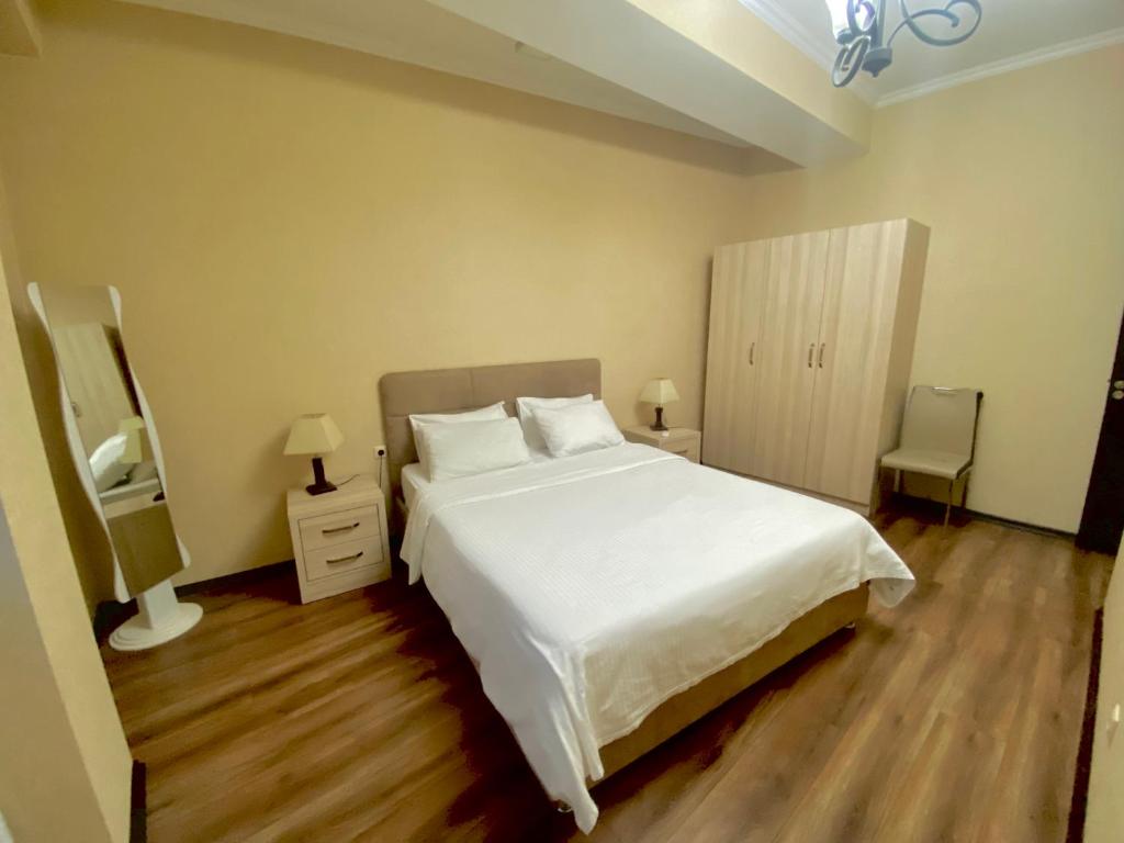 MG Apartments in Tbilisi في تبليسي: غرفة نوم بسرير ابيض كبير وارضيات خشبية