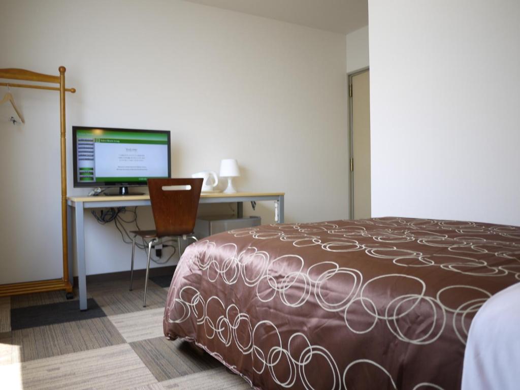 een slaapkamer met een bed en een bureau met een computer bij Hotel Select Inn Shikoku Chuo in Shikokuchuo