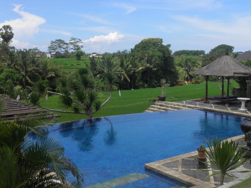 a large swimming pool with a lawn and trees at Bumi Ubud Resort in Ubud