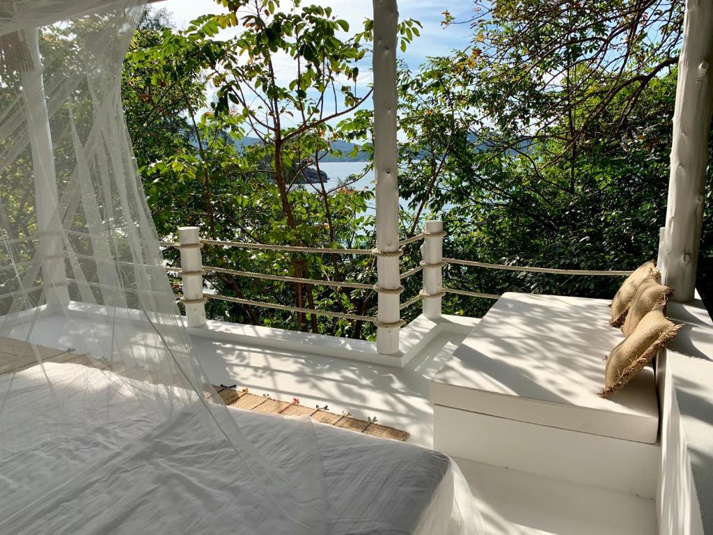 Coconut Beach Bungalows في تشالوكلوم: وجود دبدوب يجلس على سرير في الشرفة