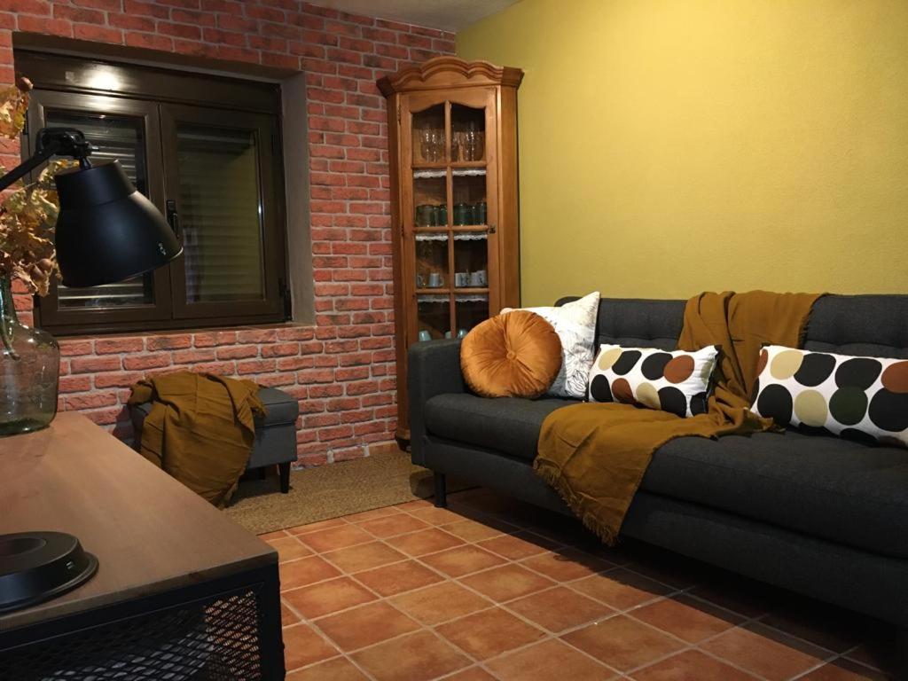 sala de estar con sofá y pared de ladrillo en El Balcón de Sotero y María, en Prádena de Atienza