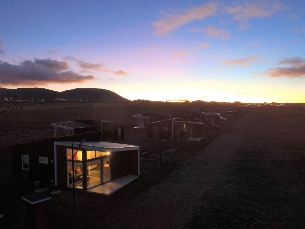 a house in a field with the sunset in the background at CABAÑAS PAMPAS AUSTRALES in Puerto Natales
