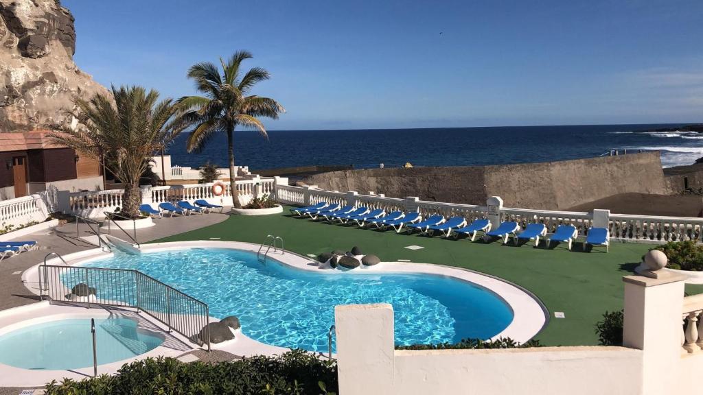 une piscine avec des chaises et l'océan en arrière-plan dans l'établissement Vivienda con encanto, en un complejo con piscina, à La Estrella