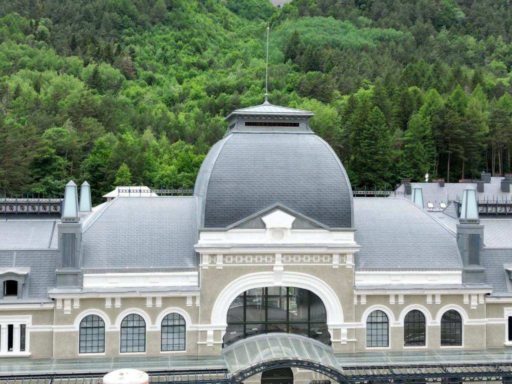 ein großes Gebäude mit grauem Dach und einem Berg in der Unterkunft WIFI COMO EN TU CASA Canfranc Estación in Canfranc-Estación