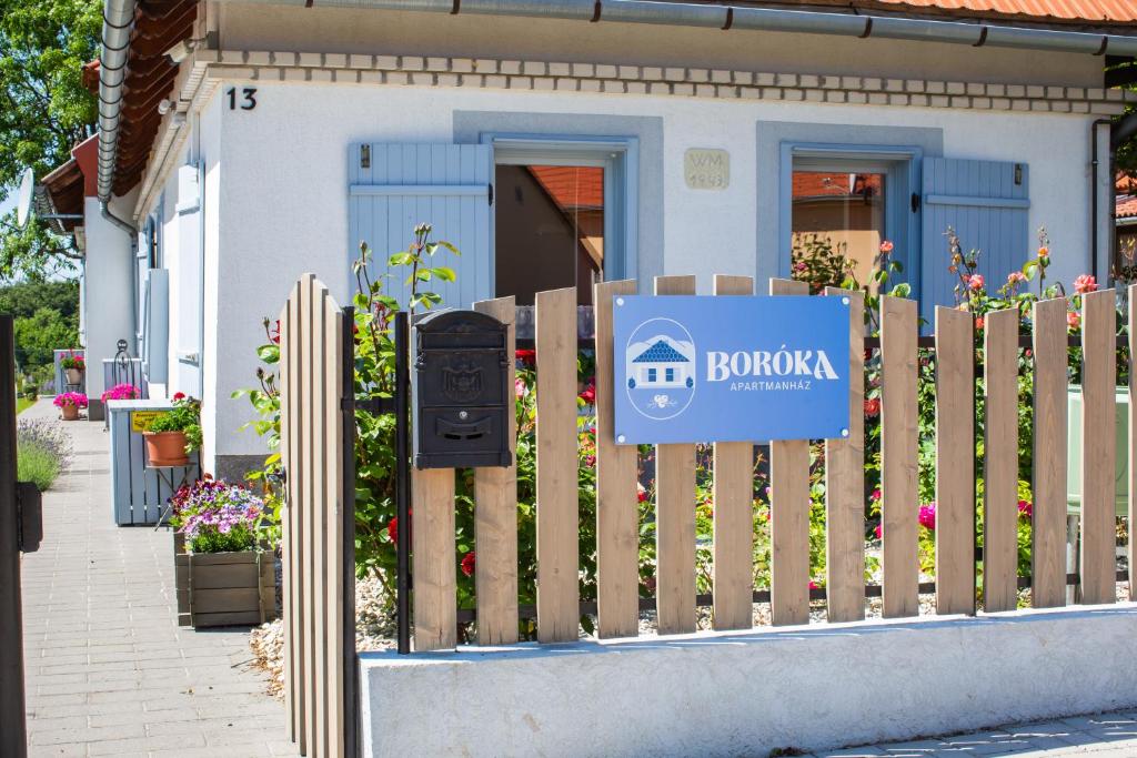 ein Schild auf einem Zaun vor einem Haus in der Unterkunft Boróka Apartmanház in Hárskút