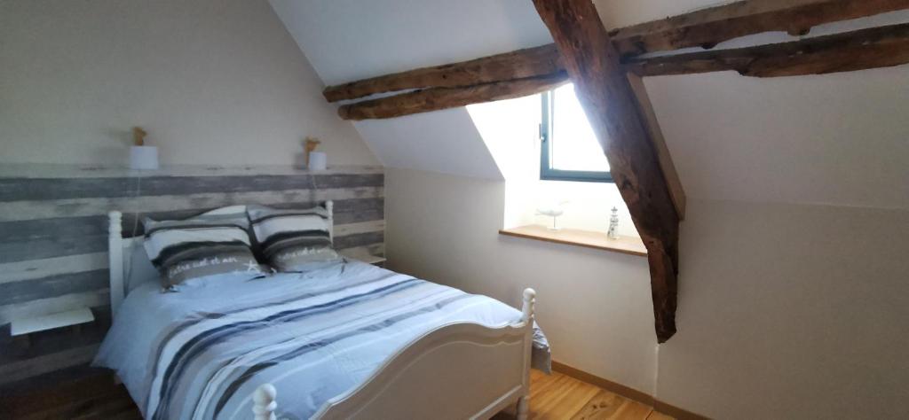 um quarto com uma cama branca e uma janela em gîte Les Châtaigniers entre terre et mer em Pleucadeuc