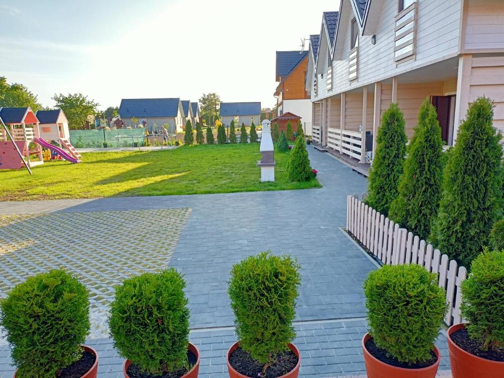 Une rangée d'arbres en pots à côté d'un bâtiment dans l'établissement Domki Platinium Sianożęty, à Sianożęty