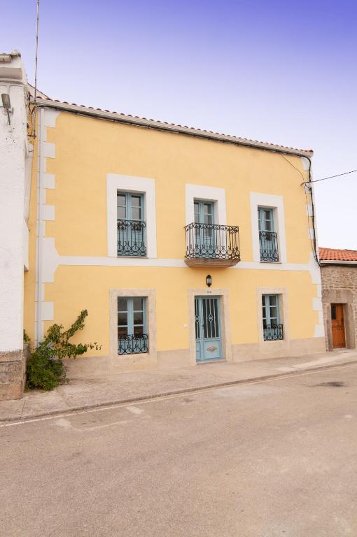 a yellow building with windows and balconies on a street at Casa Amarilla Arribes in Cerezal de Peñahorcada
