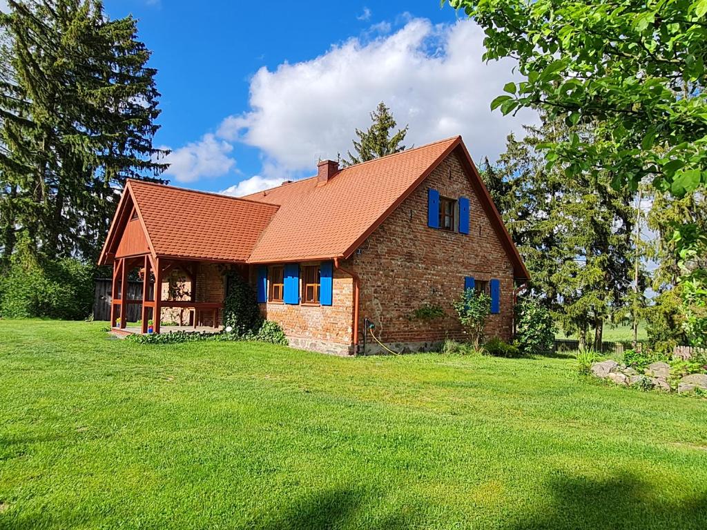 una casa de ladrillo con techo rojo en un campo verde en Wyspa Świerków, en Lipusz