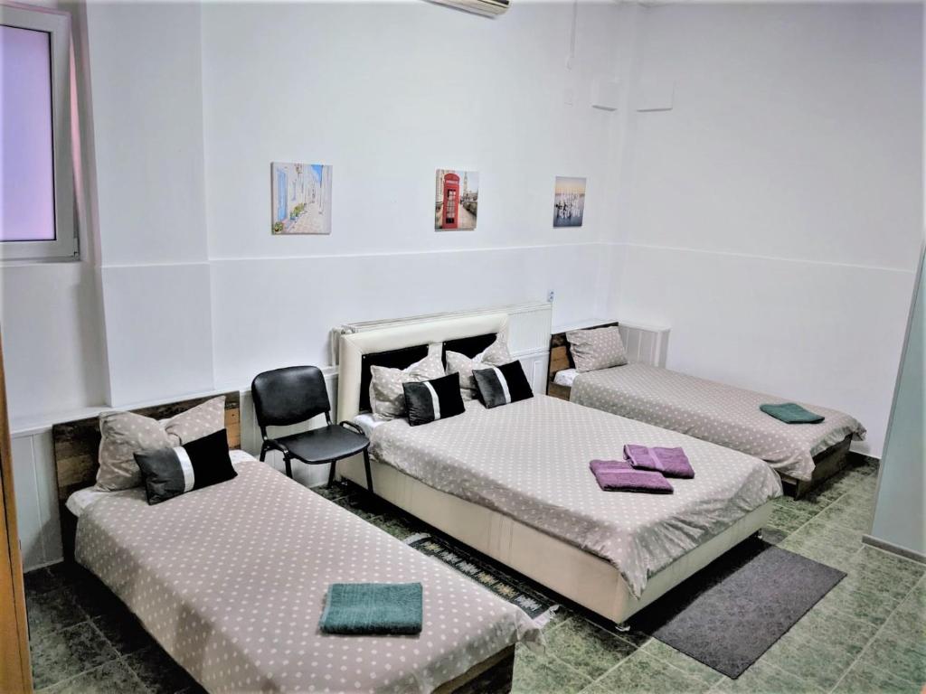 Habitación con 2 camas y una silla. en Casa Agape, en Piteşti