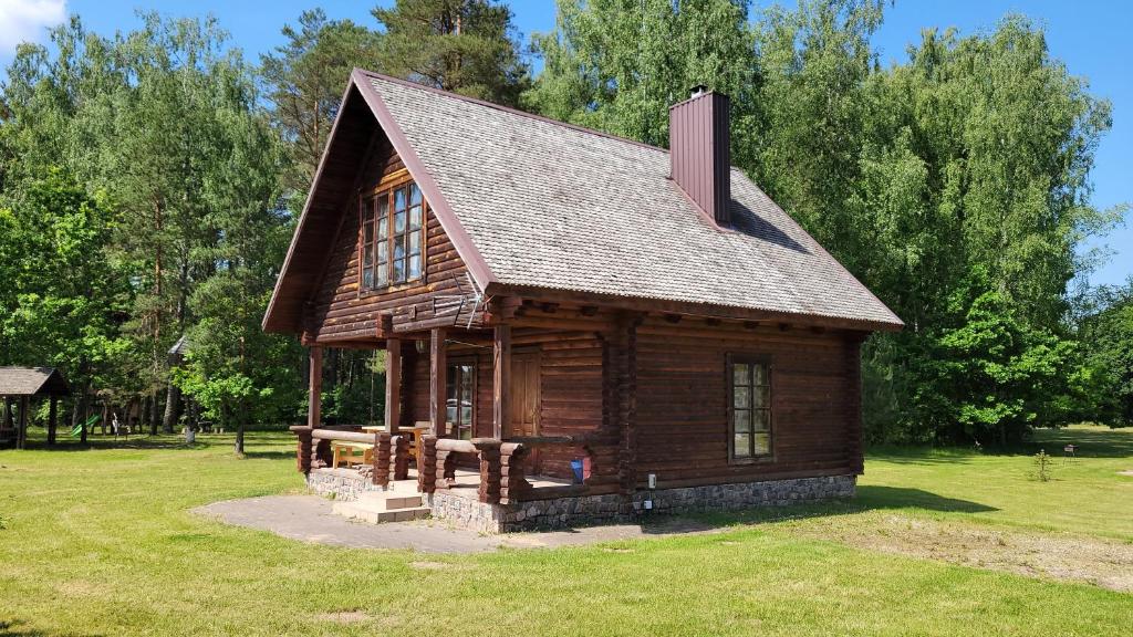 una cabaña de madera sentada en la parte superior de un exuberante campo verde en Sodyba Paštys, en Vozgėliai