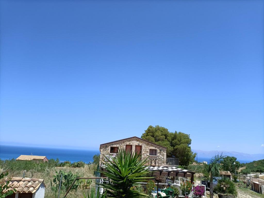 an old house on a hill with the ocean in the background at Casolare La Torre in Scopello