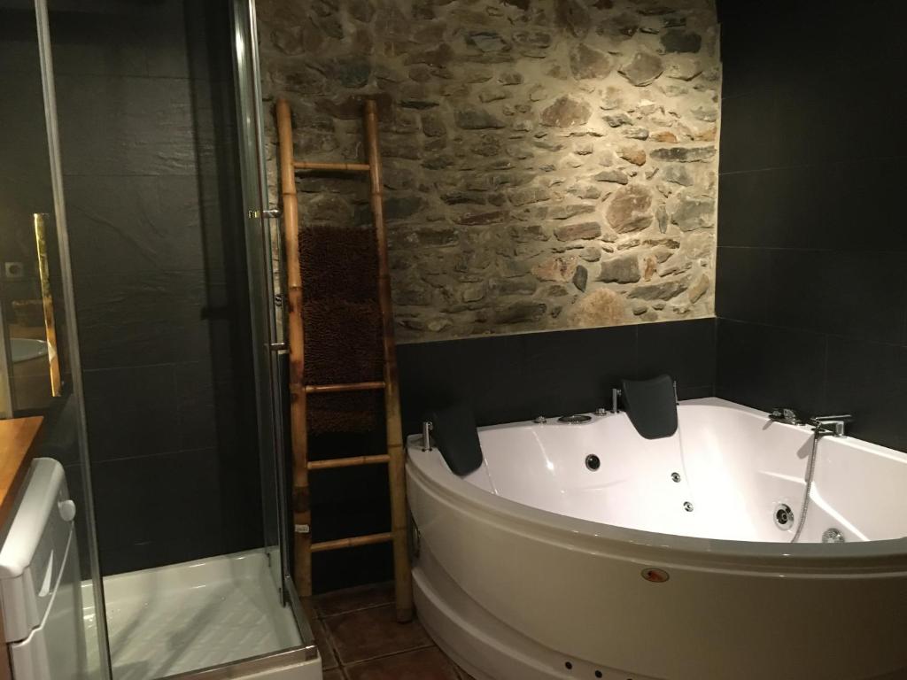 W łazience z kamienną ścianą znajduje się wanna. w obiekcie La Maison du Carlit w mieście Porté-Puymorens