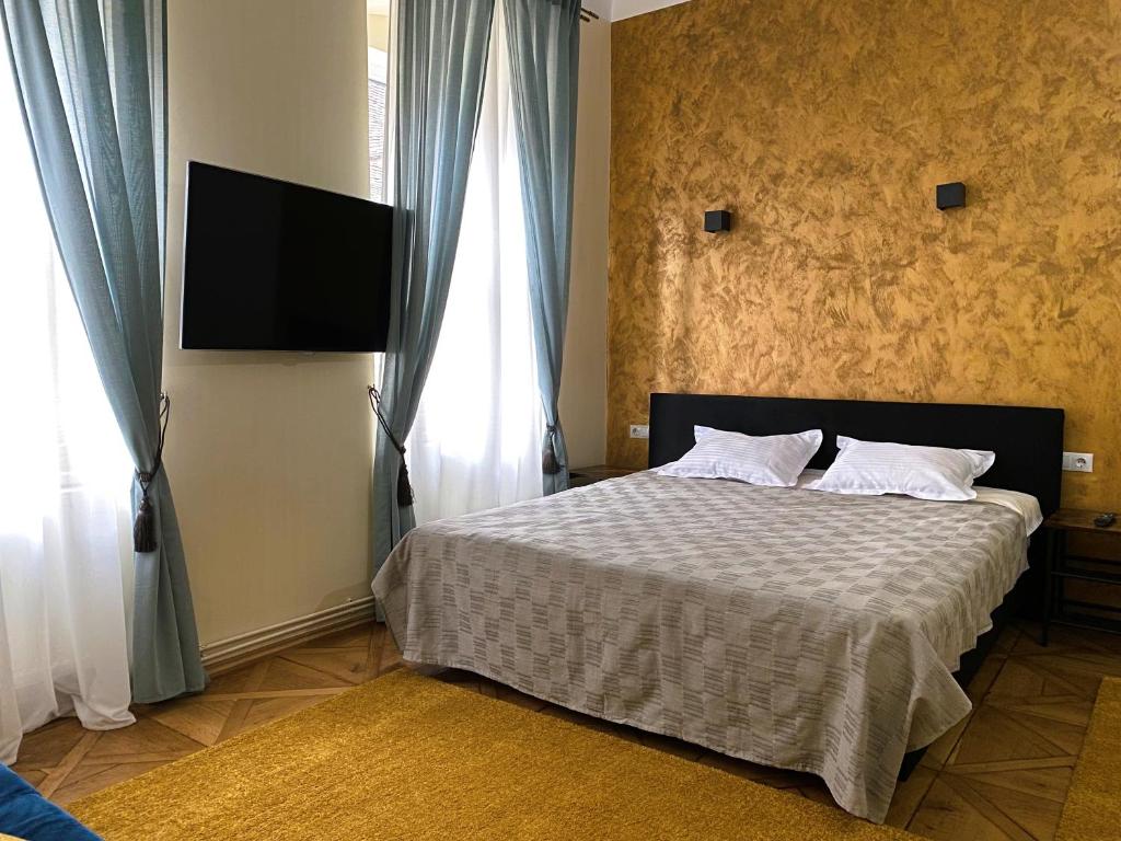een slaapkamer met een bed en een tv aan de muur bij BOEM 2 Sibiu Old Town in Sibiu