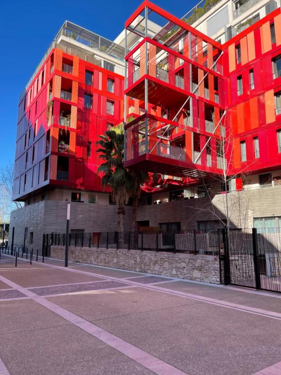 um edifício vermelho no lado de uma rua em T2 Port Marianne avec balcon et place de parking em Montpellier