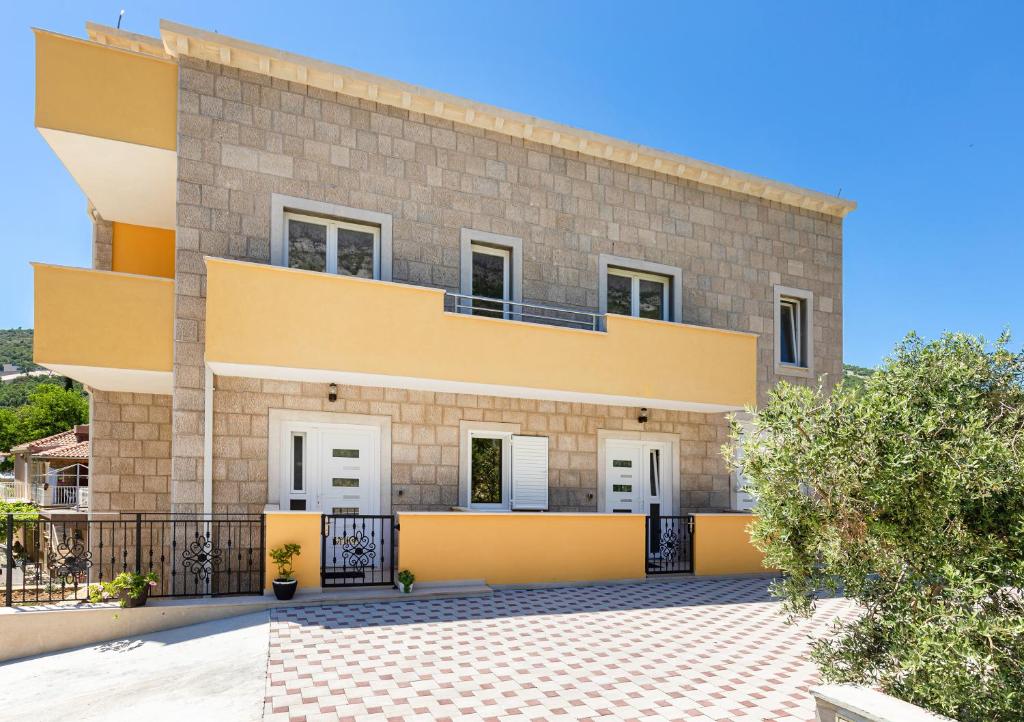 una casa con facciata gialla e bianca di Olive tree apartment 1 a Prijevor