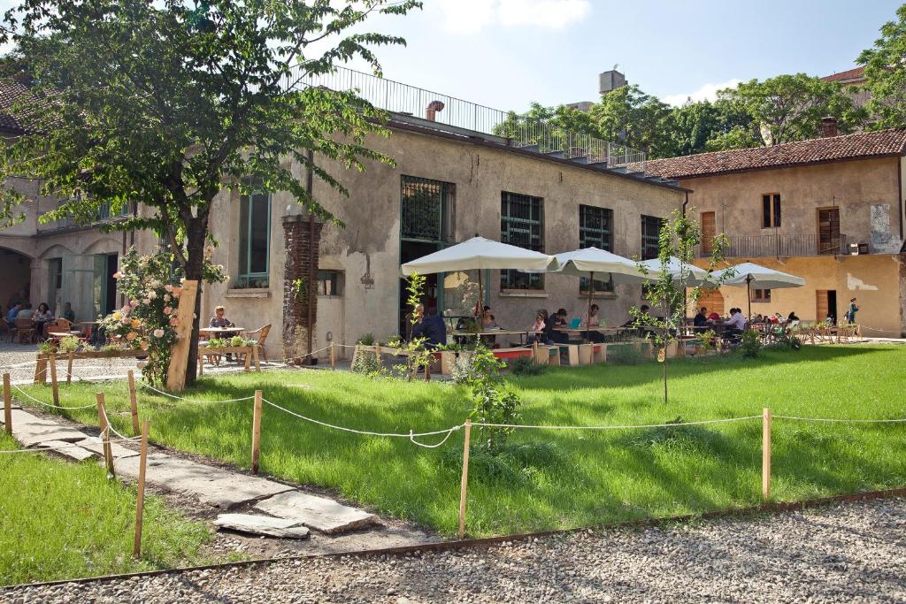 ogród z ludźmi siedzącymi poza budynkiem w obiekcie Un posto a Milano - guesthouse all'interno di una cascina del 700 w Mediolanie