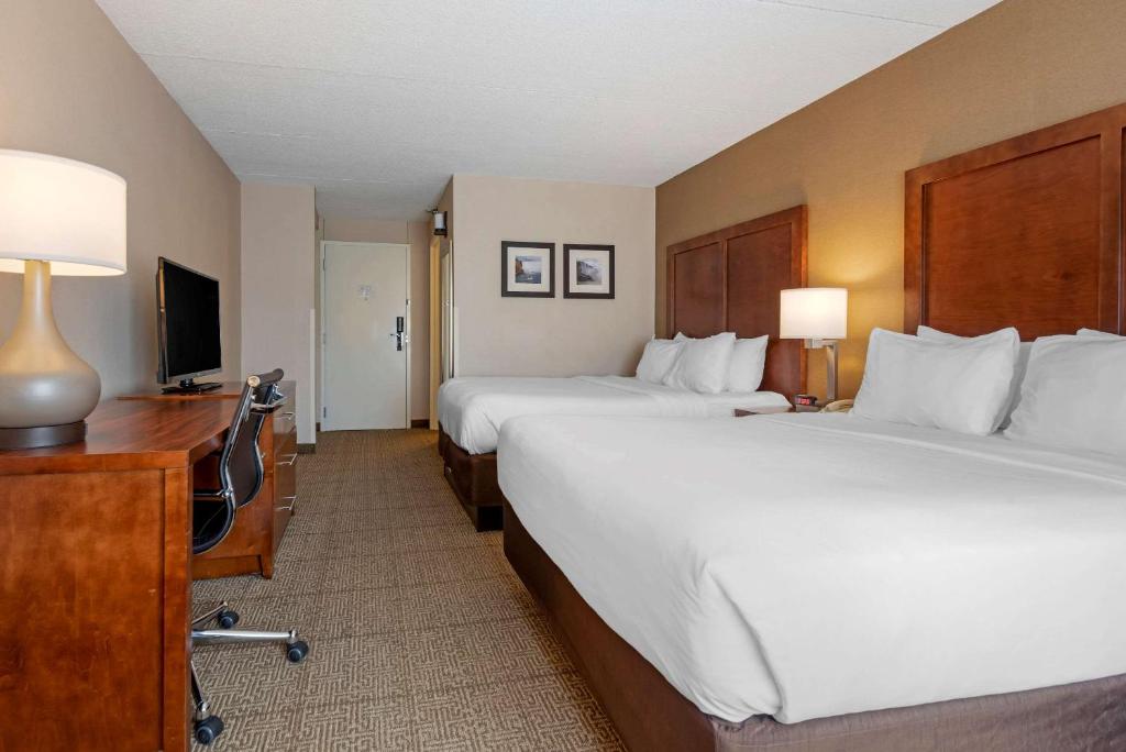 a hotel room with two beds and a desk and a television at Comfort Inn The Pointe in Niagara Falls