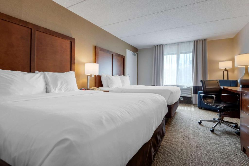 a hotel room with two beds and a desk at Comfort Inn The Pointe in Niagara Falls