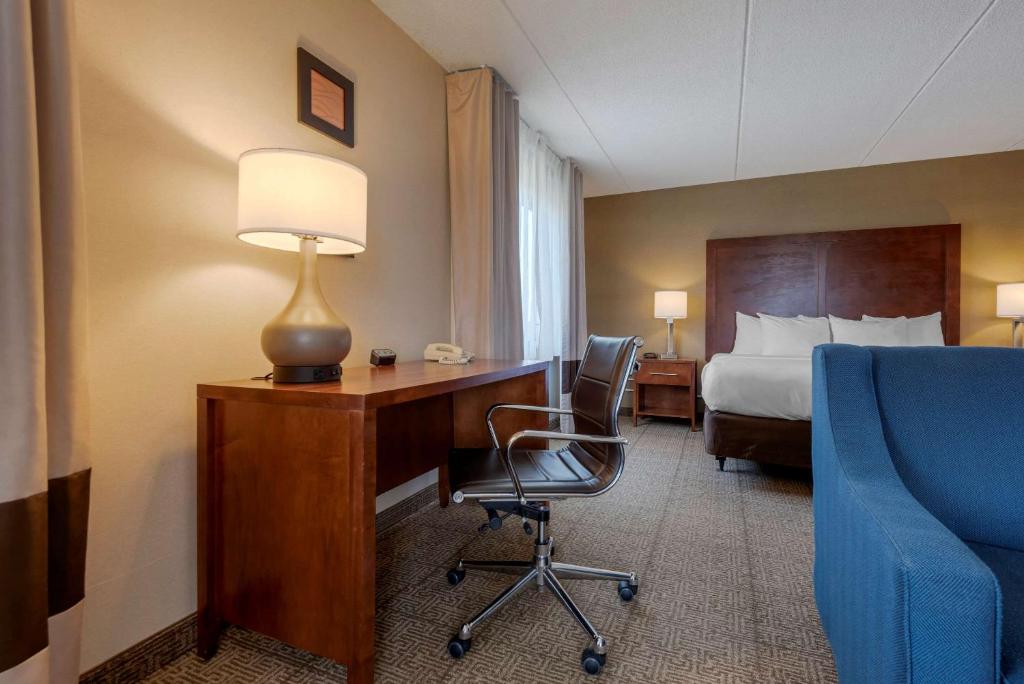 a hotel room with a desk and a bed and a lamp at Comfort Inn The Pointe in Niagara Falls