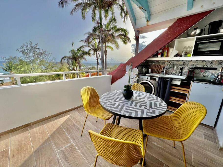 una sala da pranzo con tavolo e sedie gialle di Ti kaz COCO DOUCEUW PIERRE ET VACANCES sea view a Sainte-Anne