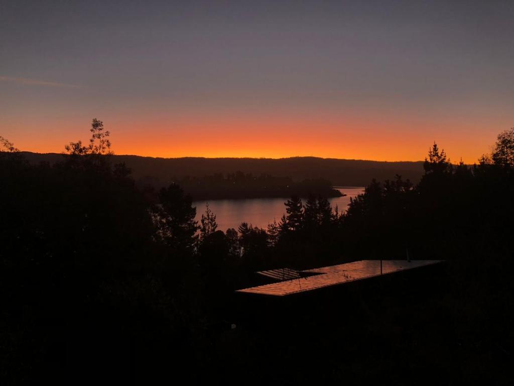 una puesta de sol sobre un lago con un barco en primer plano en Vichuquén Mágico, en Vichuquén