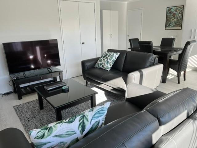 a living room with a black leather couch and a tv at Rotorua Central Hosted B&B in Rotorua