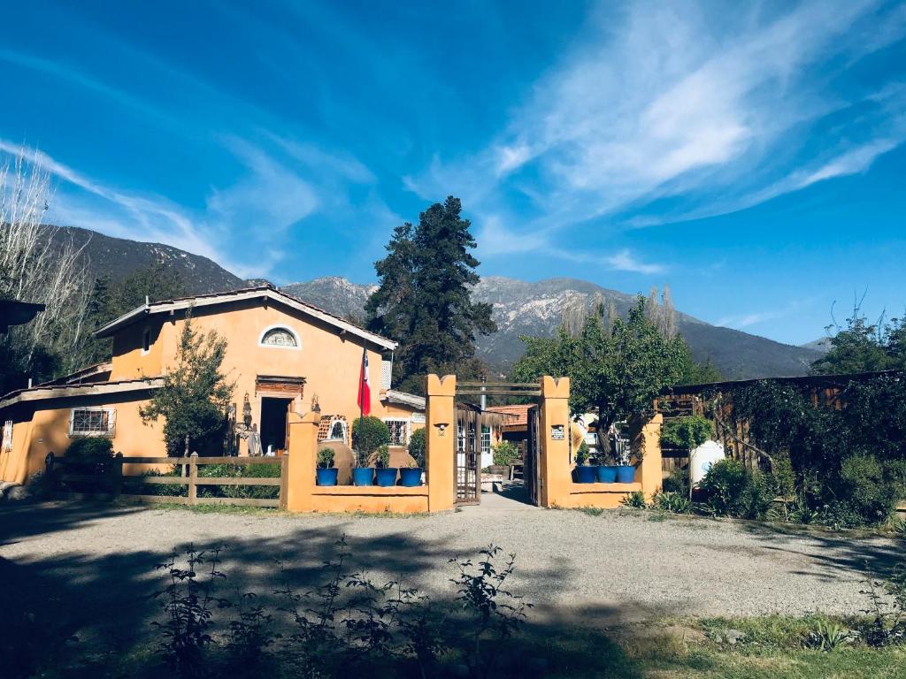 a house with a wooden gate and mountains in the background at Hotel La Calma De Rita - Pirque in Pirque