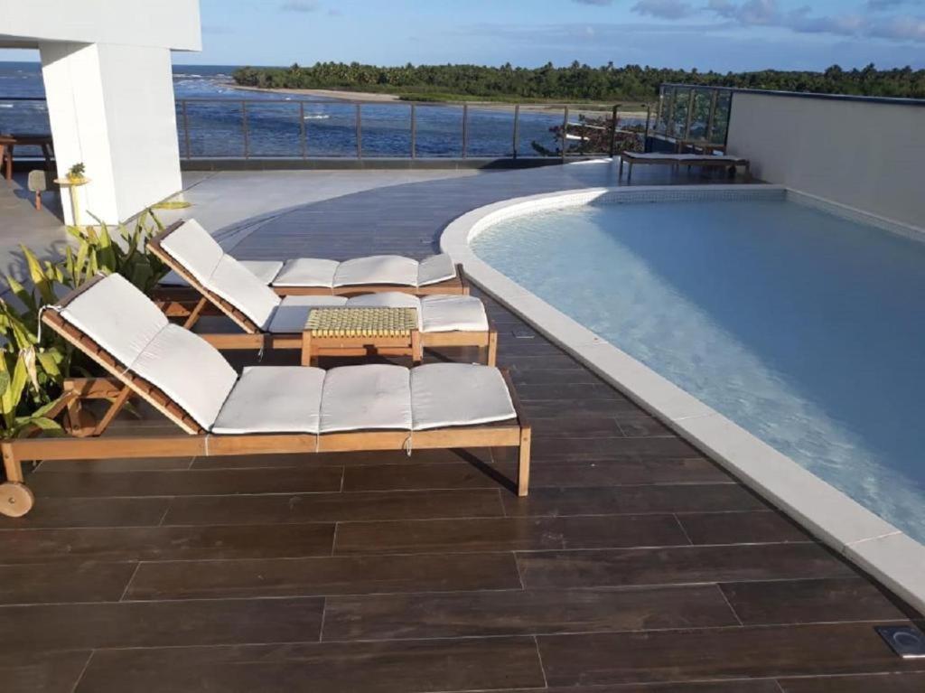 uma piscina com espreguiçadeiras ao lado de uma piscina em FLAT BEIRA MAR BARRA DE JANGADA RECIFE ANDAR ALTO no Recife