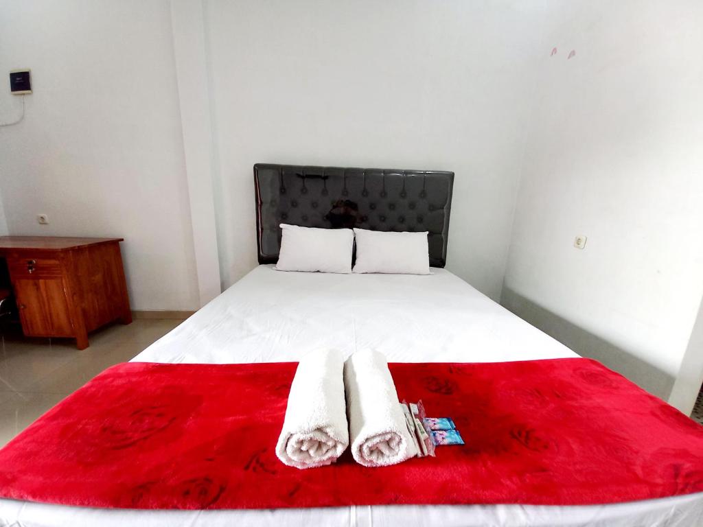 a bed with a red blanket and two towels on it at Harmony House Syariah near Alun Alun Pati Mitra RedDoorz in Pati