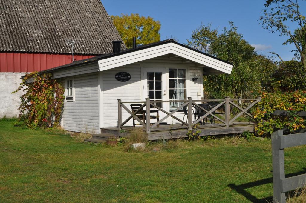 un petit cottage blanc avec une grange rouge dans l'établissement Rusthållaregården i Edenryd, à Bromölla