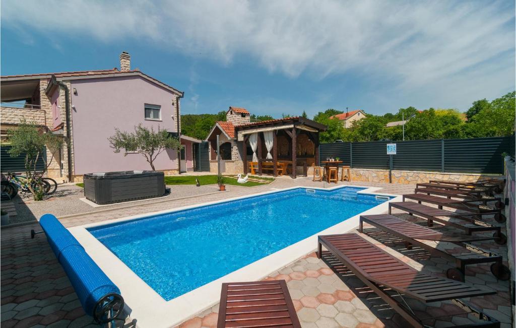 a swimming pool with chairs and a house at Beautiful Home In Hrvace With Heated Swimming Pool in Hrvace