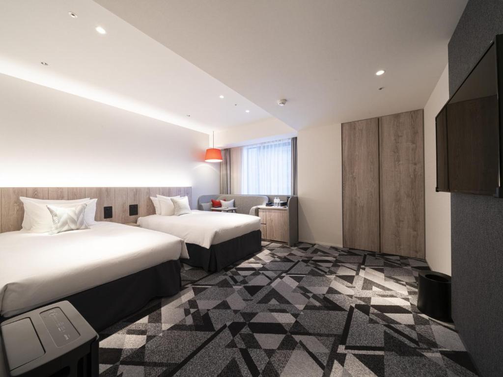 富山市にあるホテルJALシティ富山のベッド2台とソファが備わるホテルルームです。