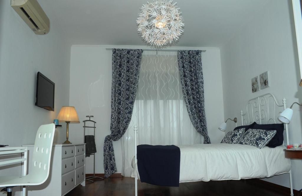 a bedroom with a white bed and a chandelier at Apartment Oltremarestudios in Naples