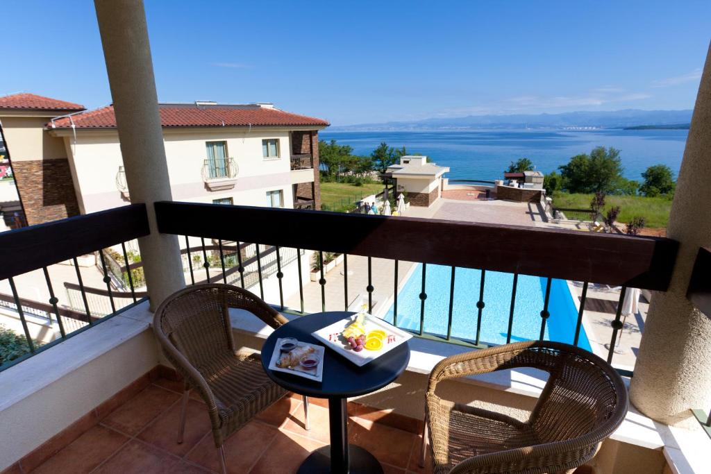 a balcony with a table and chairs and a view of the water at Blue Waves Resort in Malinska
