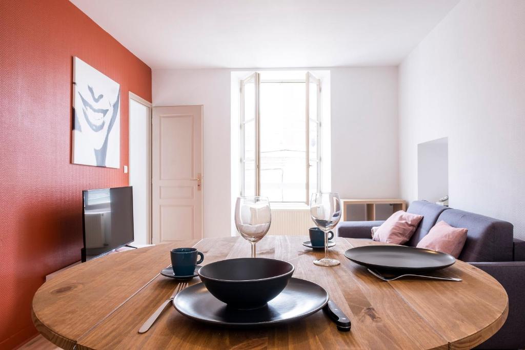 - une table en bois avec 2 assiettes et des verres à vin dans l'établissement Gîte Terracotta de Segré ✰ cuisine ✰ chambre (lit queen size) ✰ salon, à Segré