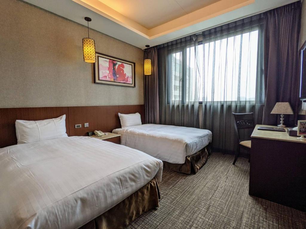 a hotel room with two beds and a window at Guanko Hotel in Chiayi City