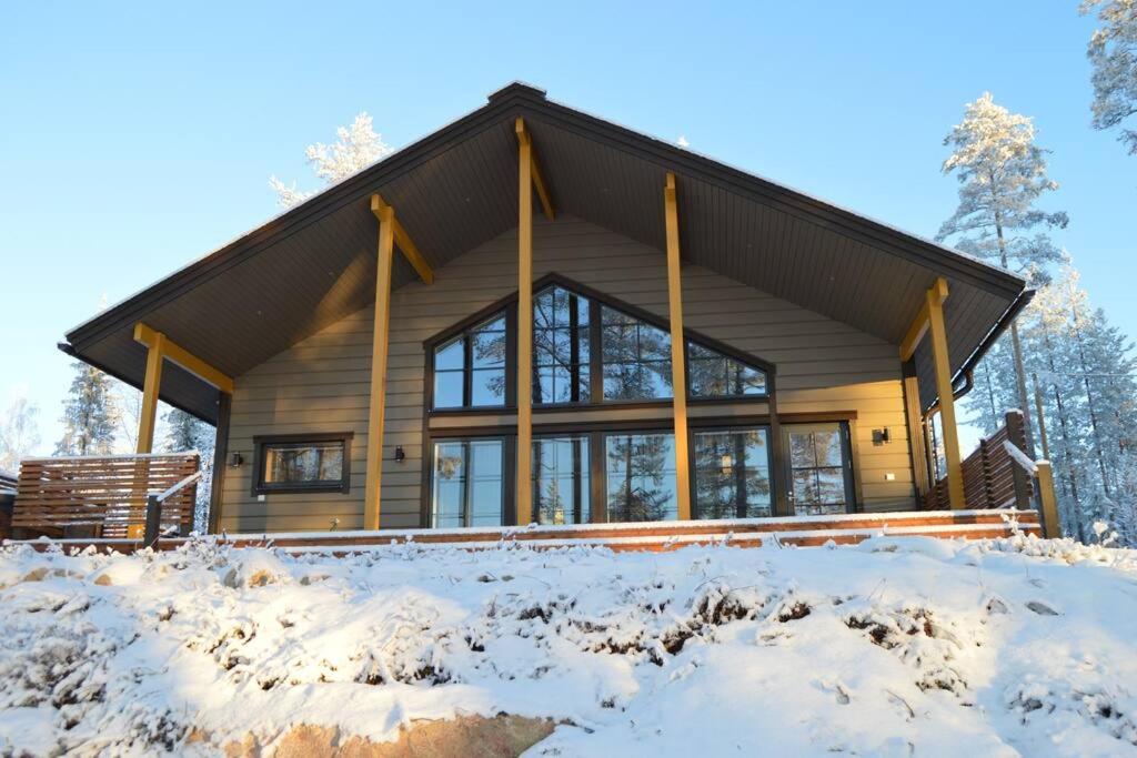 une maison en rondins dans la neige dans les bois dans l'établissement Villa Vasa - new luxury villa next to lake, à Meltaus